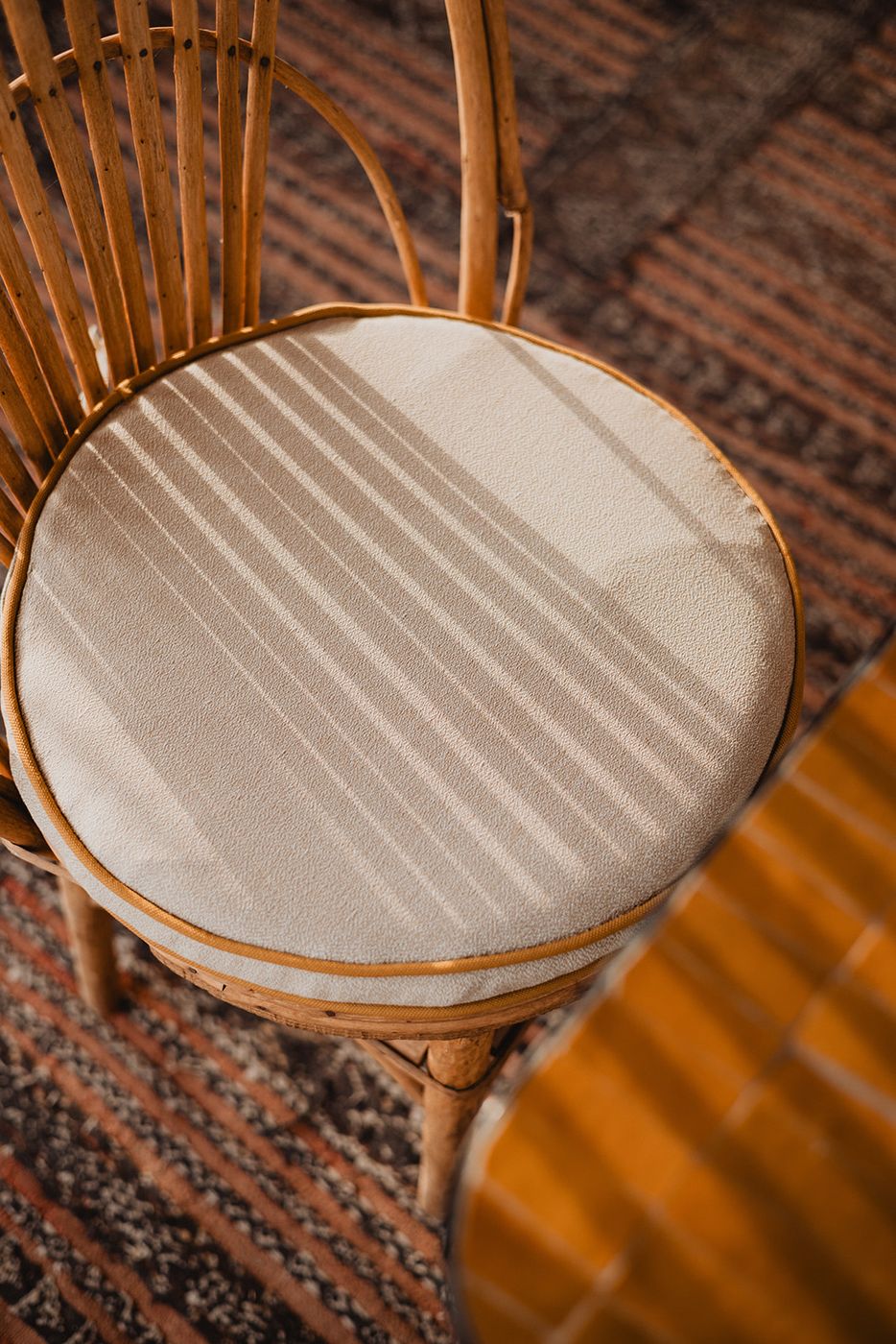 Rattan seat striped with shadow on a Berber rug